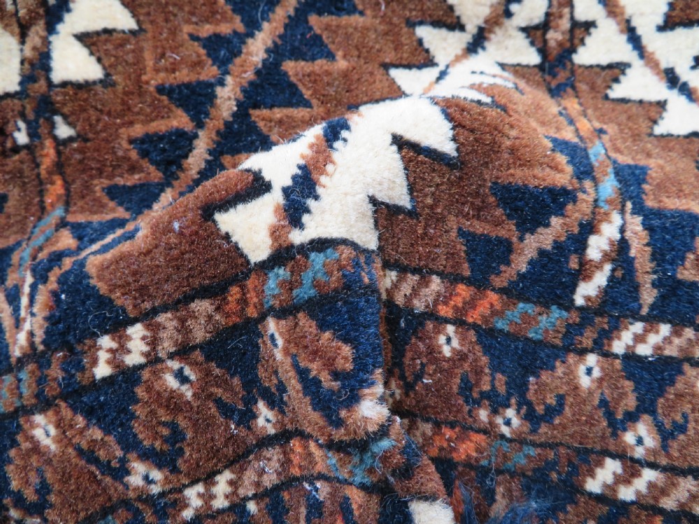 A hand-woven Yomut Turkmen Ok Bash tent-pole bag featuring geometric chevron patterns in rust brown, indigo, and cream wool, finished with braided ties and multi-coloured tassels. View XVI