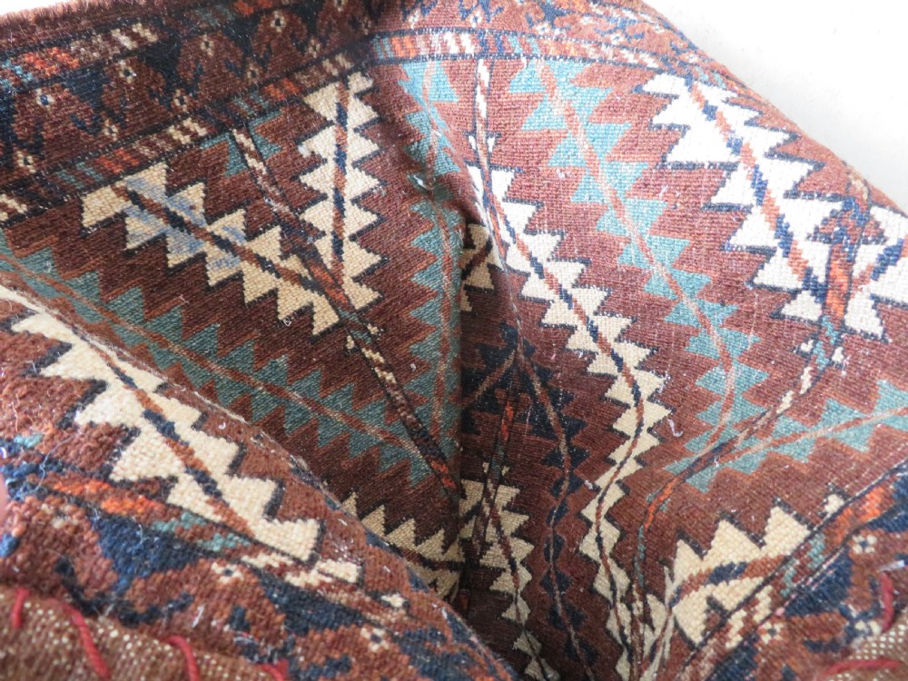 A hand-woven Yomut Turkmen Ok Bash tent-pole bag featuring geometric chevron patterns in rust brown, indigo, and cream wool, finished with braided ties and multi-coloured tassels. View XXII