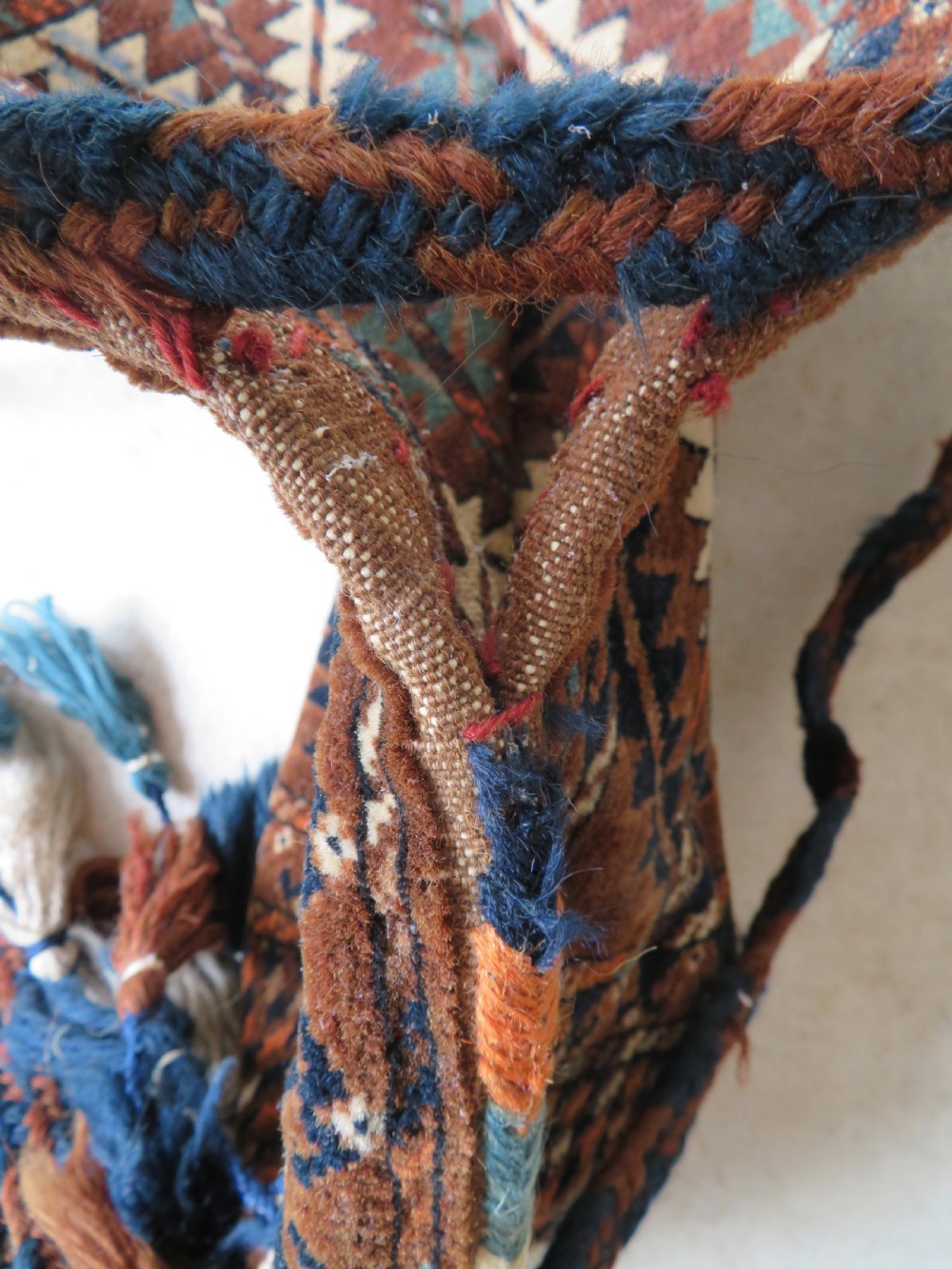 A hand-woven Yomut Turkmen Ok Bash tent-pole bag featuring geometric chevron patterns in rust brown, indigo, and cream wool, finished with braided ties and multi-coloured tassels. View XXIII