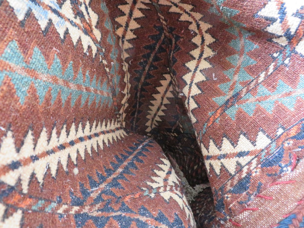 A hand-woven Yomut Turkmen Ok Bash tent-pole bag featuring geometric chevron patterns in rust brown, indigo, and cream wool, finished with braided ties and multi-coloured tassels. View XXIV