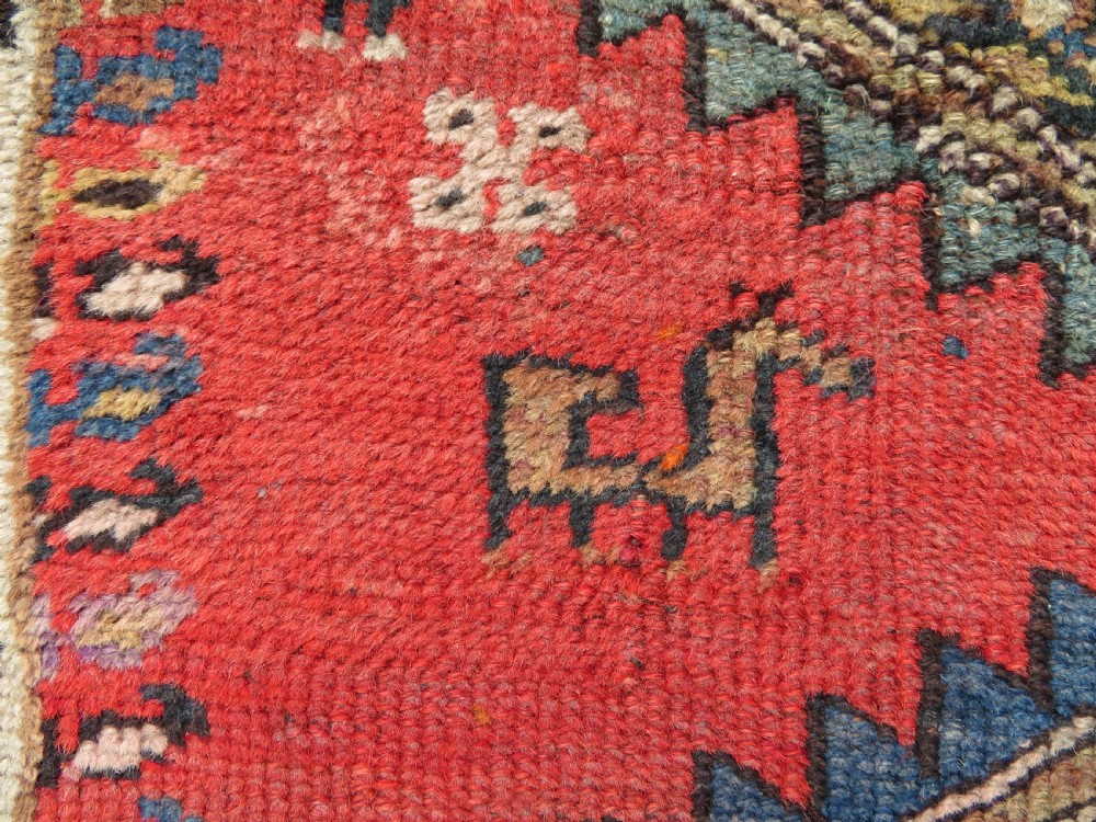 A hand-knotted antique Persian Kurdish wool runner rug with five central diamond medallions on a red field framed by a patterned ivory border. View VIII