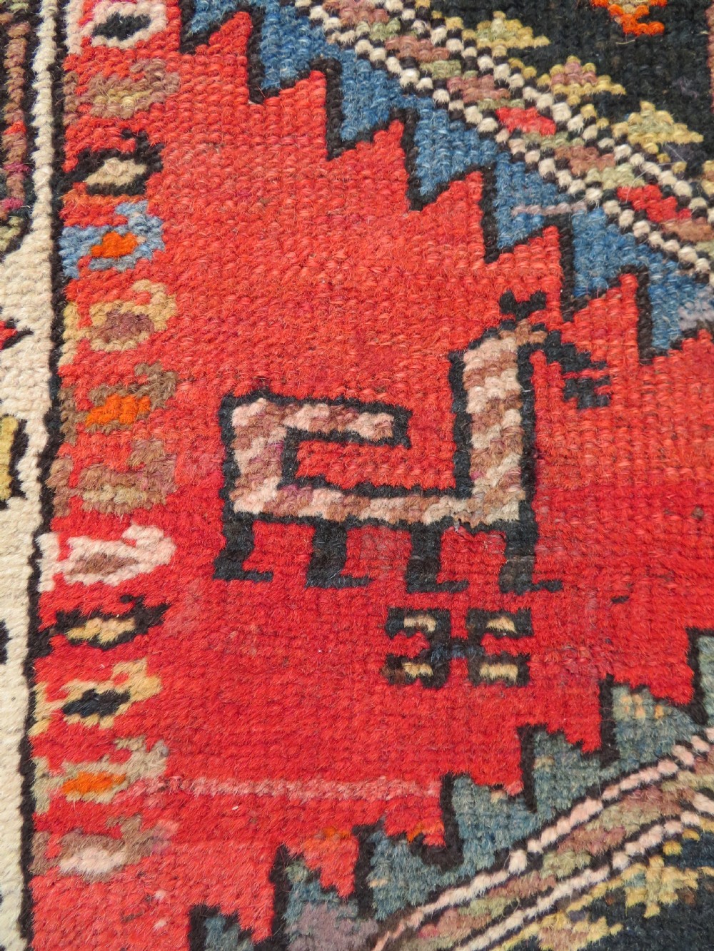 A hand-knotted antique Persian Kurdish wool runner rug with five central diamond medallions on a red field framed by a patterned ivory border. View IX