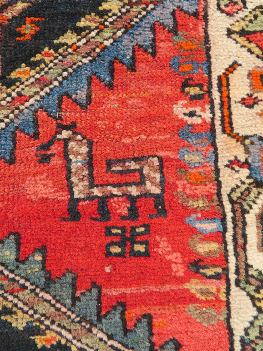 A hand-knotted antique Persian Kurdish wool runner rug with five central diamond medallions on a red field framed by a patterned ivory border. View X