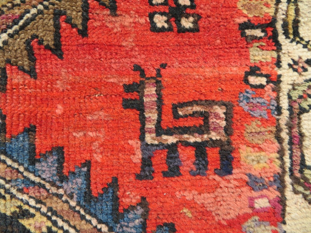A hand-knotted antique Persian Kurdish wool runner rug with five central diamond medallions on a red field framed by a patterned ivory border. View XI