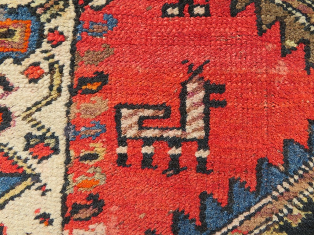 A hand-knotted antique Persian Kurdish wool runner rug with five central diamond medallions on a red field framed by a patterned ivory border. View XII