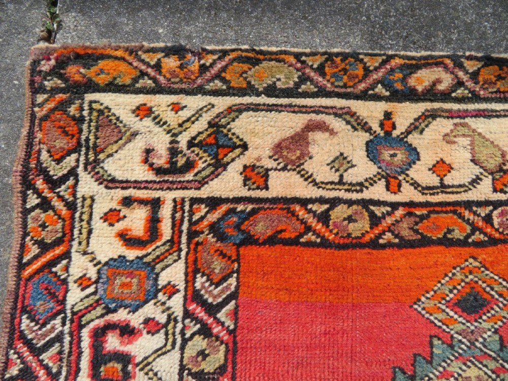 A hand-knotted antique Persian Kurdish wool runner rug with five central diamond medallions on a red field framed by a patterned ivory border. View XIII