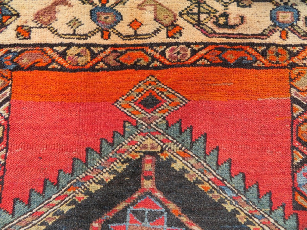 A hand-knotted antique Persian Kurdish wool runner rug with five central diamond medallions on a red field framed by a patterned ivory border. View XIV