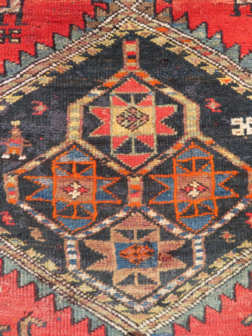 A hand-knotted antique Persian Kurdish wool runner rug with five central diamond medallions on a red field framed by a patterned ivory border. View XVII