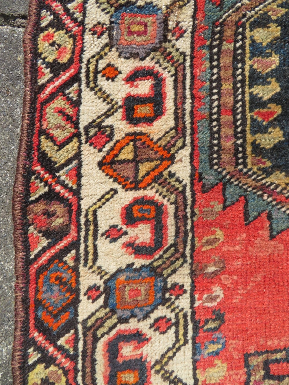 A hand-knotted antique Persian Kurdish wool runner rug with five central diamond medallions on a red field framed by a patterned ivory border. View XVIII