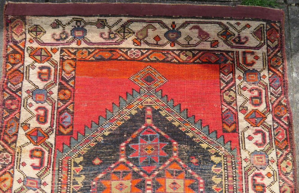 A hand-knotted antique Persian Kurdish wool runner rug with five central diamond medallions on a red field framed by a patterned ivory border. View XXII