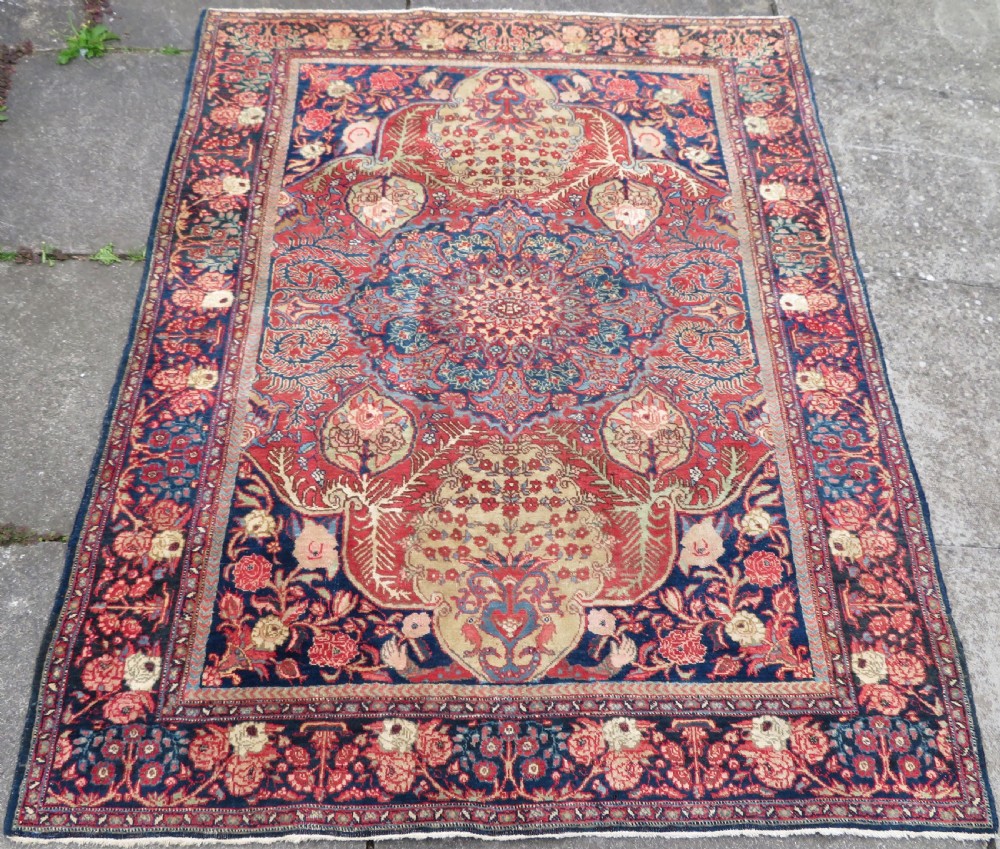 An antique hand-knotted North West Persian Tabriz rug featuring a central floral medallion surrounded by detailed terracotta red, navy blue, and cream motifs.