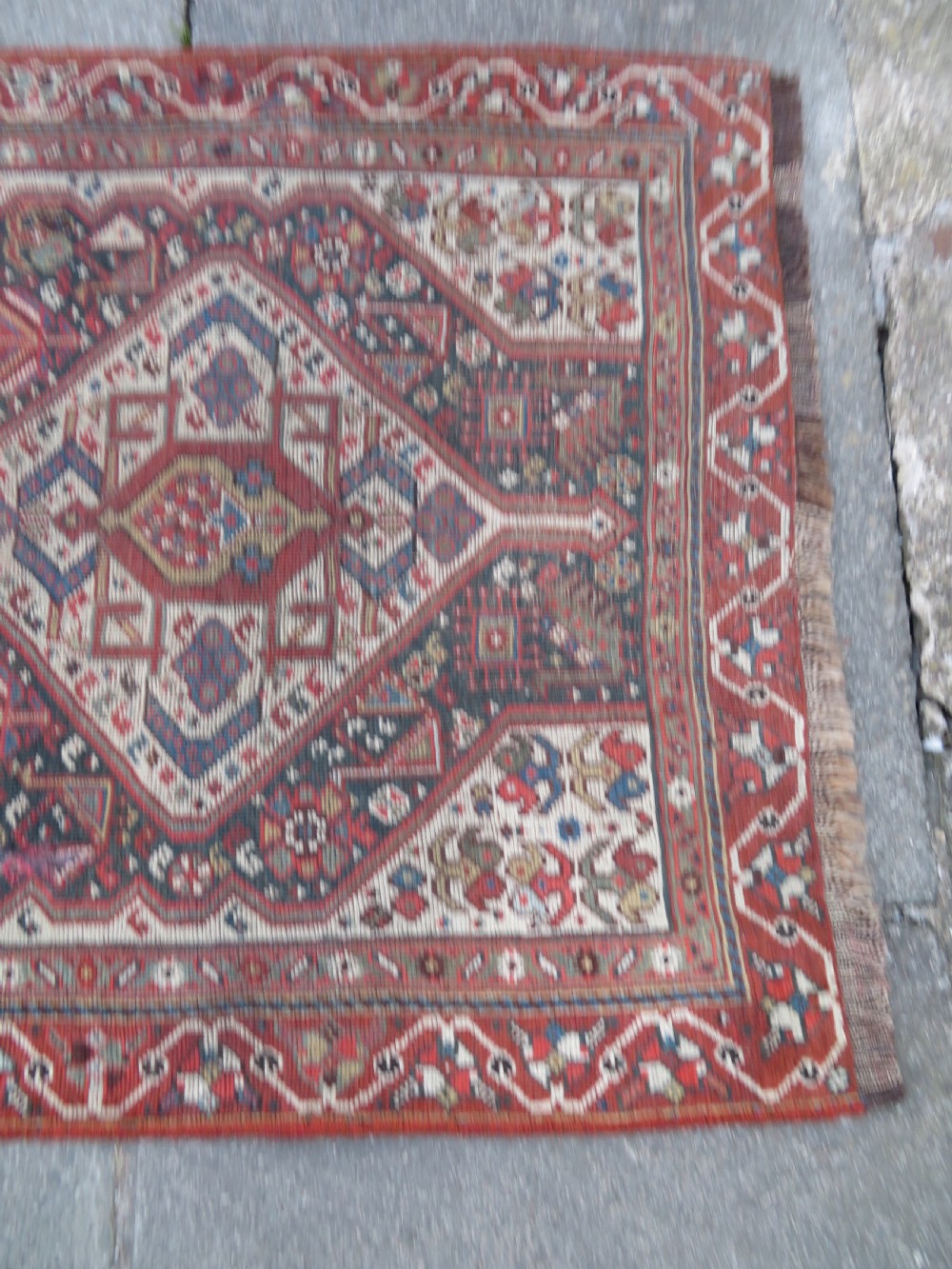 An antique hand-knotted Qashqai wool runner rug featuring repeating geometric diamond medallions in red, blue, and cream tones. View VI