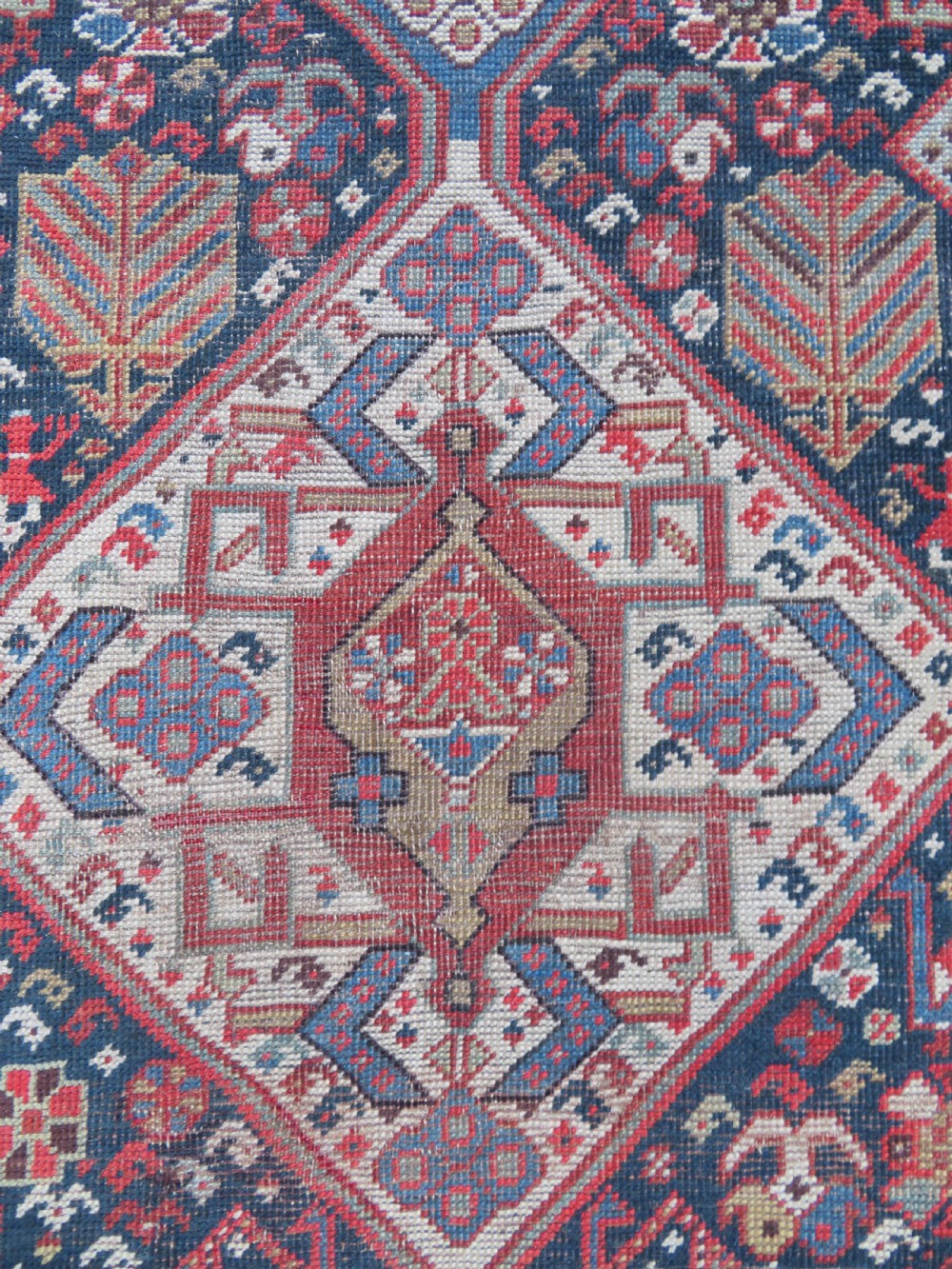 An antique hand-knotted Qashqai wool runner rug featuring repeating geometric diamond medallions in red, blue, and cream tones. View IX