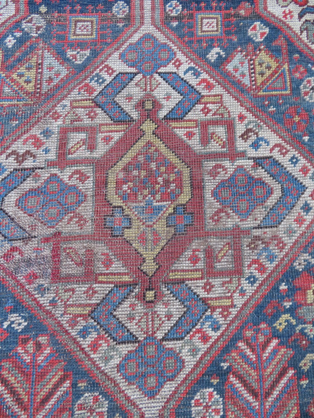 An antique hand-knotted Qashqai wool runner rug featuring repeating geometric diamond medallions in red, blue, and cream tones. View XI