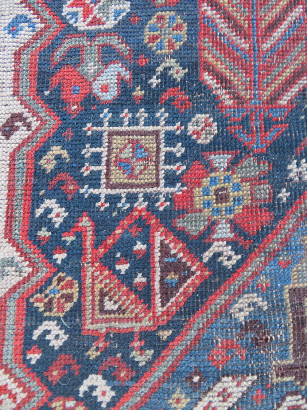 An antique hand-knotted Qashqai wool runner rug featuring repeating geometric diamond medallions in red, blue, and cream tones. View XIII