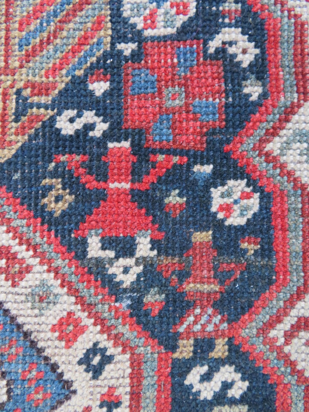 An antique hand-knotted Qashqai wool runner rug featuring repeating geometric diamond medallions in red, blue, and cream tones. View XV
