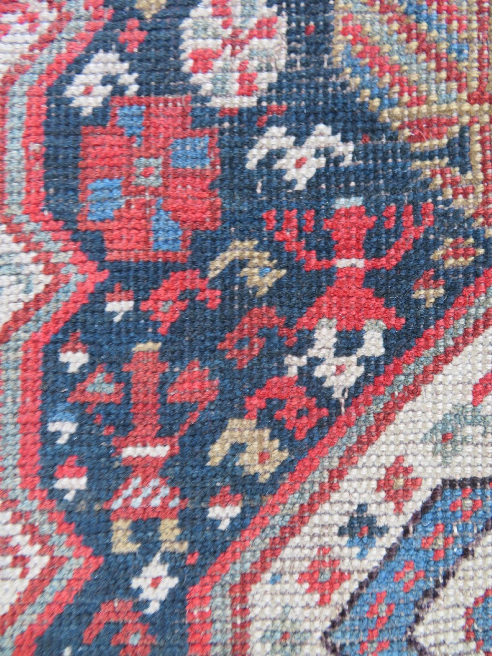 An antique hand-knotted Qashqai wool runner rug featuring repeating geometric diamond medallions in red, blue, and cream tones. View XVI
