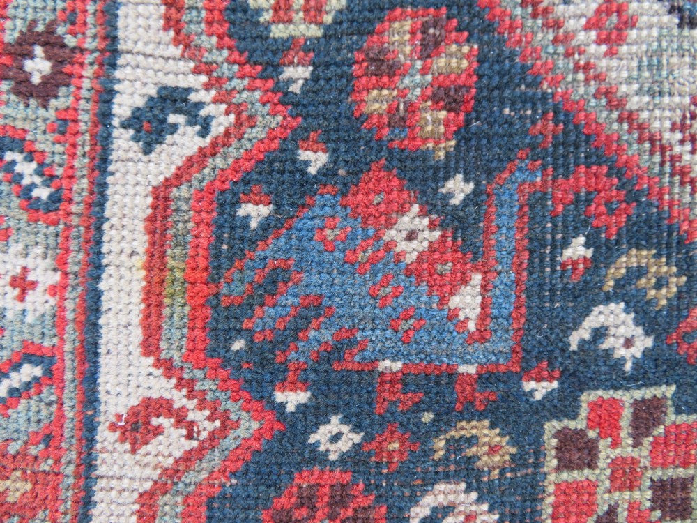 An antique hand-knotted Qashqai wool runner rug featuring repeating geometric diamond medallions in red, blue, and cream tones. View XVII