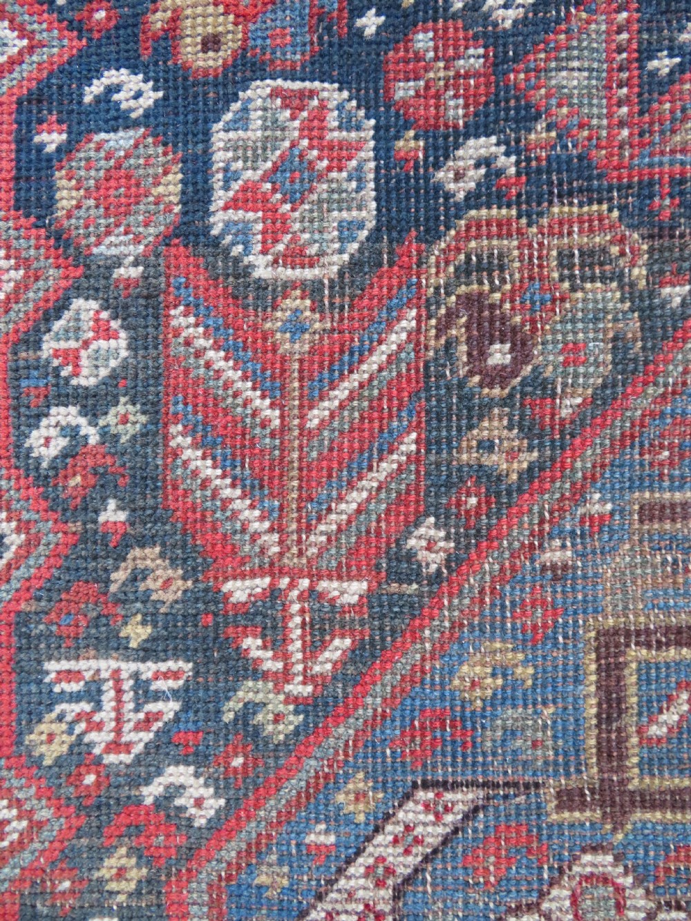 An antique hand-knotted Qashqai wool runner rug featuring repeating geometric diamond medallions in red, blue, and cream tones. View XVIII