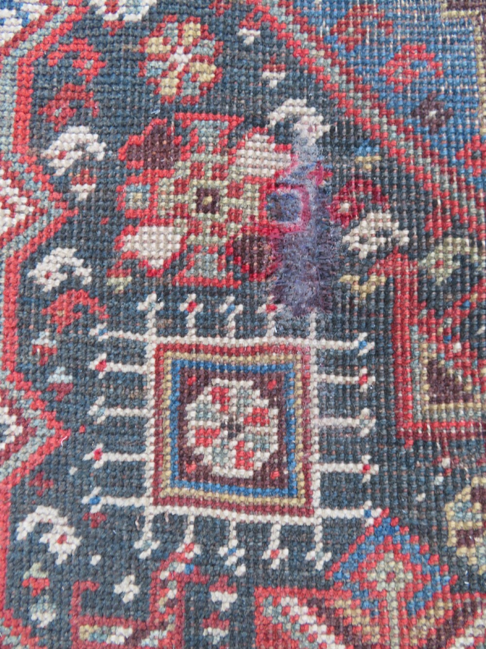 An antique hand-knotted Qashqai wool runner rug featuring repeating geometric diamond medallions in red, blue, and cream tones. View XIX