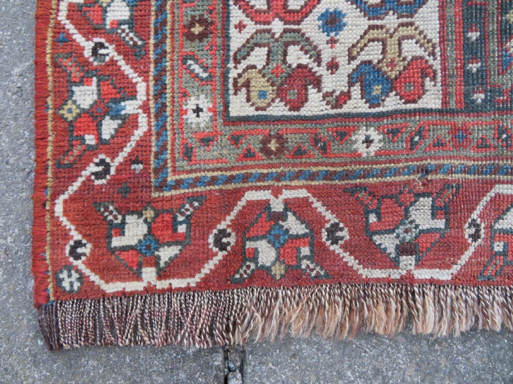 An antique hand-knotted Qashqai wool runner rug featuring repeating geometric diamond medallions in red, blue, and cream tones. View XX