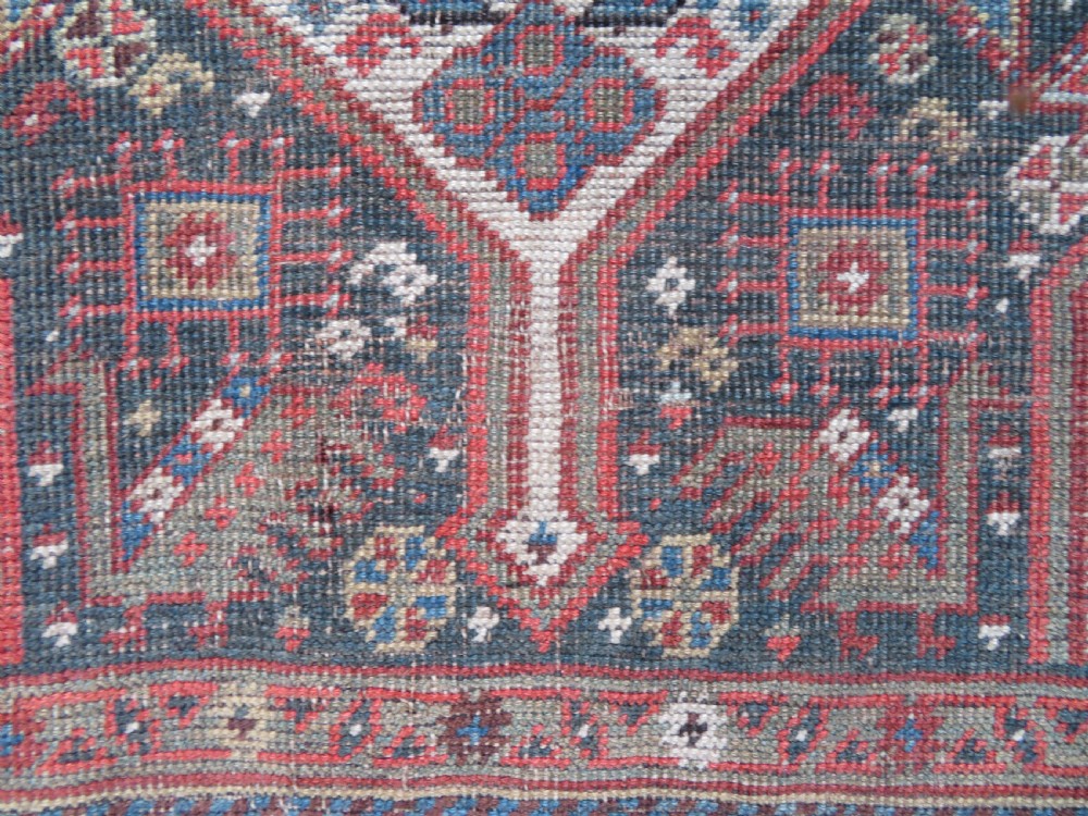 An antique hand-knotted Qashqai wool runner rug featuring repeating geometric diamond medallions in red, blue, and cream tones. View XXII