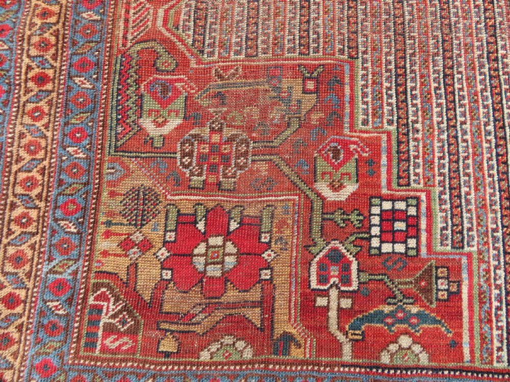 An antique hand-knotted South Persian Khamseh rug featuring a central diamond medallion surrounded by a striped field and geometric borders in shades of terracotta red, navy blue, and cream. View V
