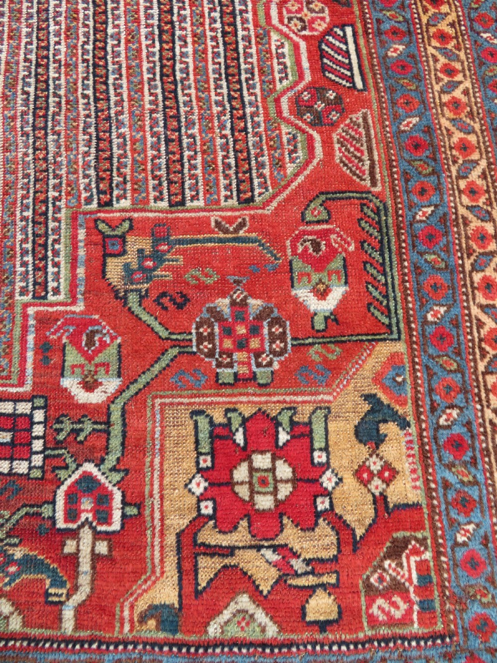 An antique hand-knotted South Persian Khamseh rug featuring a central diamond medallion surrounded by a striped field and geometric borders in shades of terracotta red, navy blue, and cream. View VI