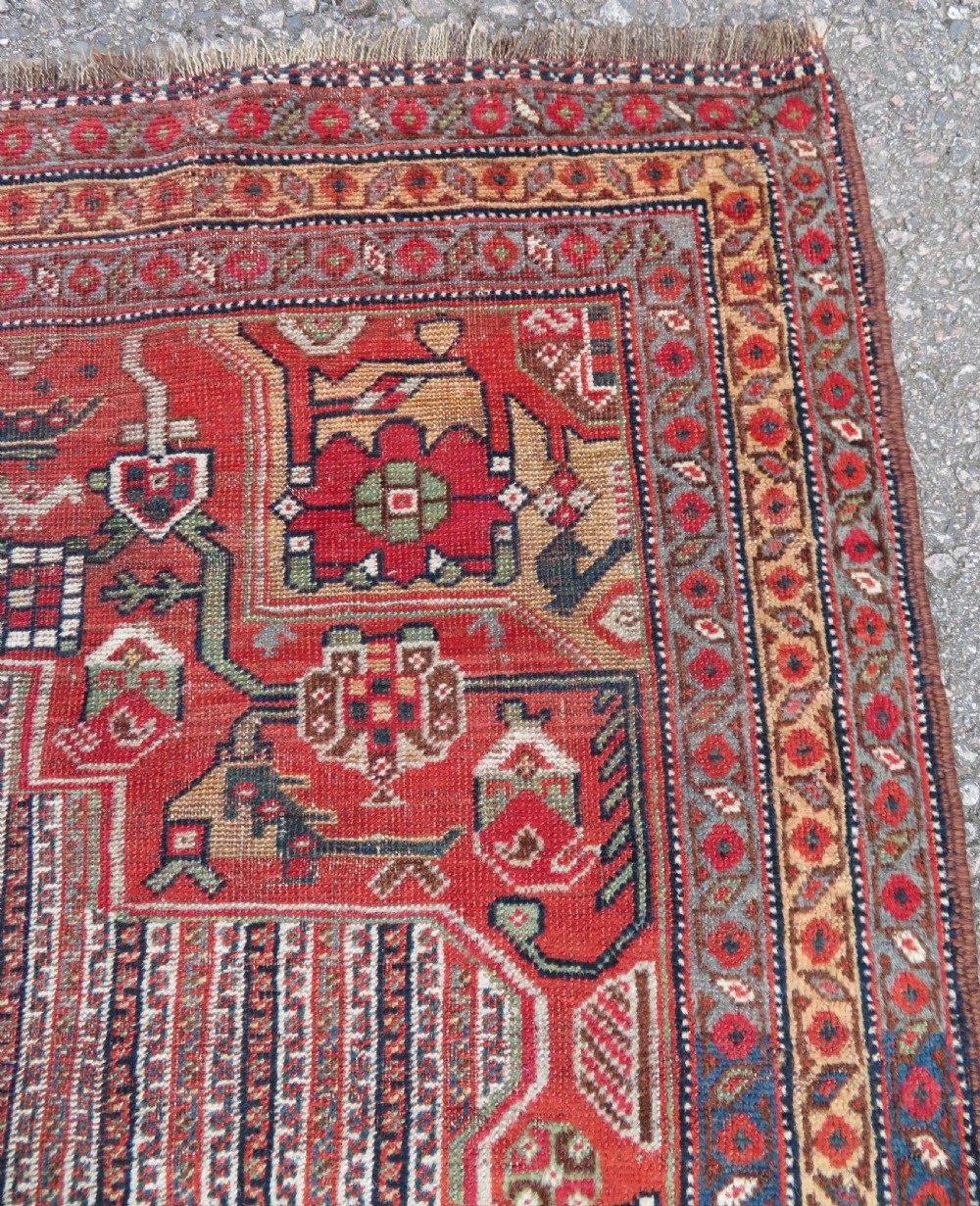 An antique hand-knotted South Persian Khamseh rug featuring a central diamond medallion surrounded by a striped field and geometric borders in shades of terracotta red, navy blue, and cream. View VII
