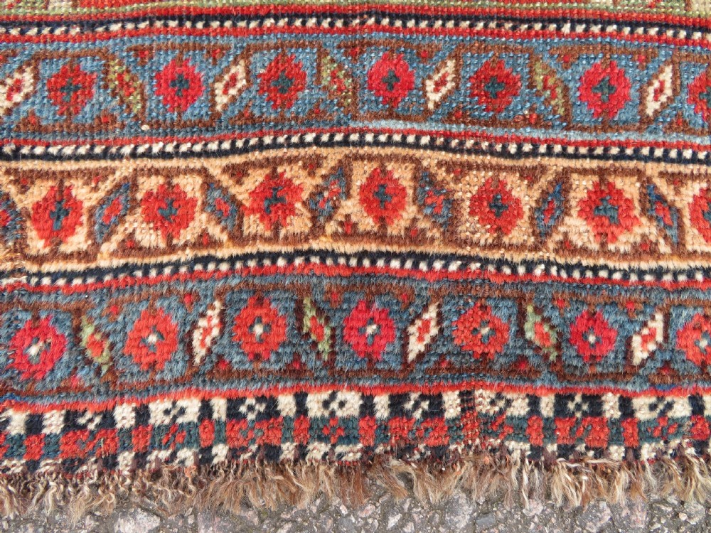 An antique hand-knotted South Persian Khamseh rug featuring a central diamond medallion surrounded by a striped field and geometric borders in shades of terracotta red, navy blue, and cream. View XII