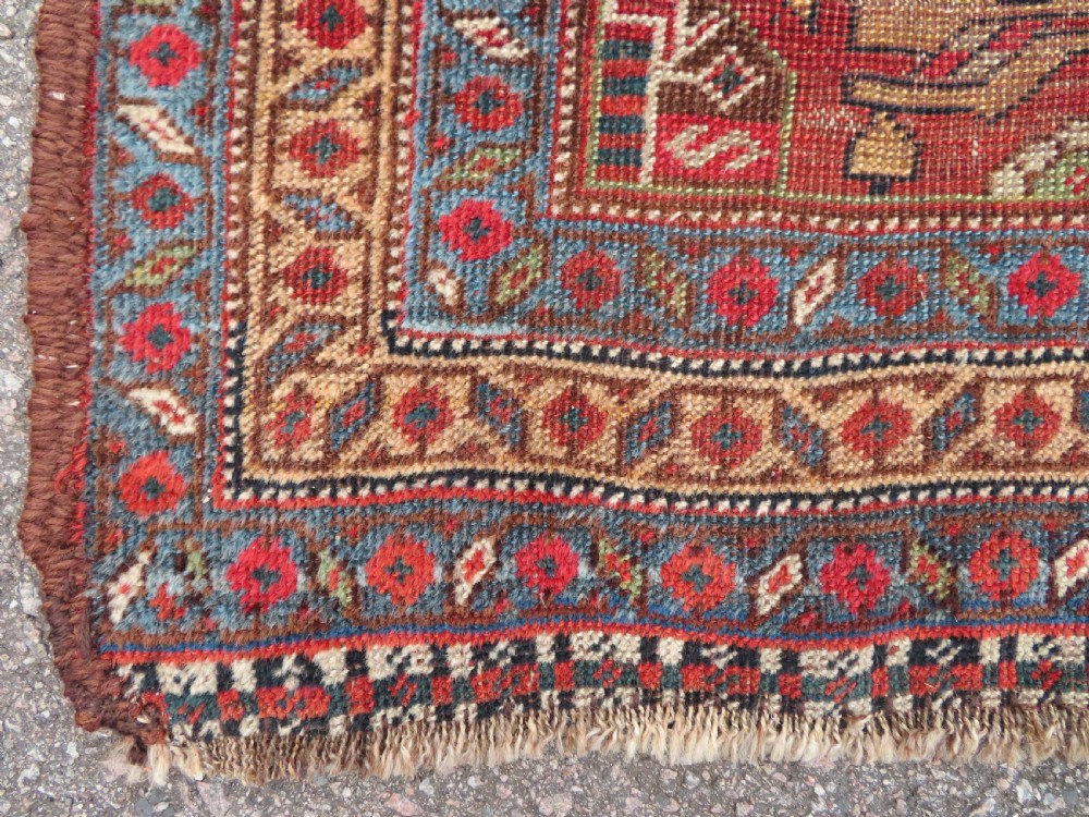An antique hand-knotted South Persian Khamseh rug featuring a central diamond medallion surrounded by a striped field and geometric borders in shades of terracotta red, navy blue, and cream. View XIII