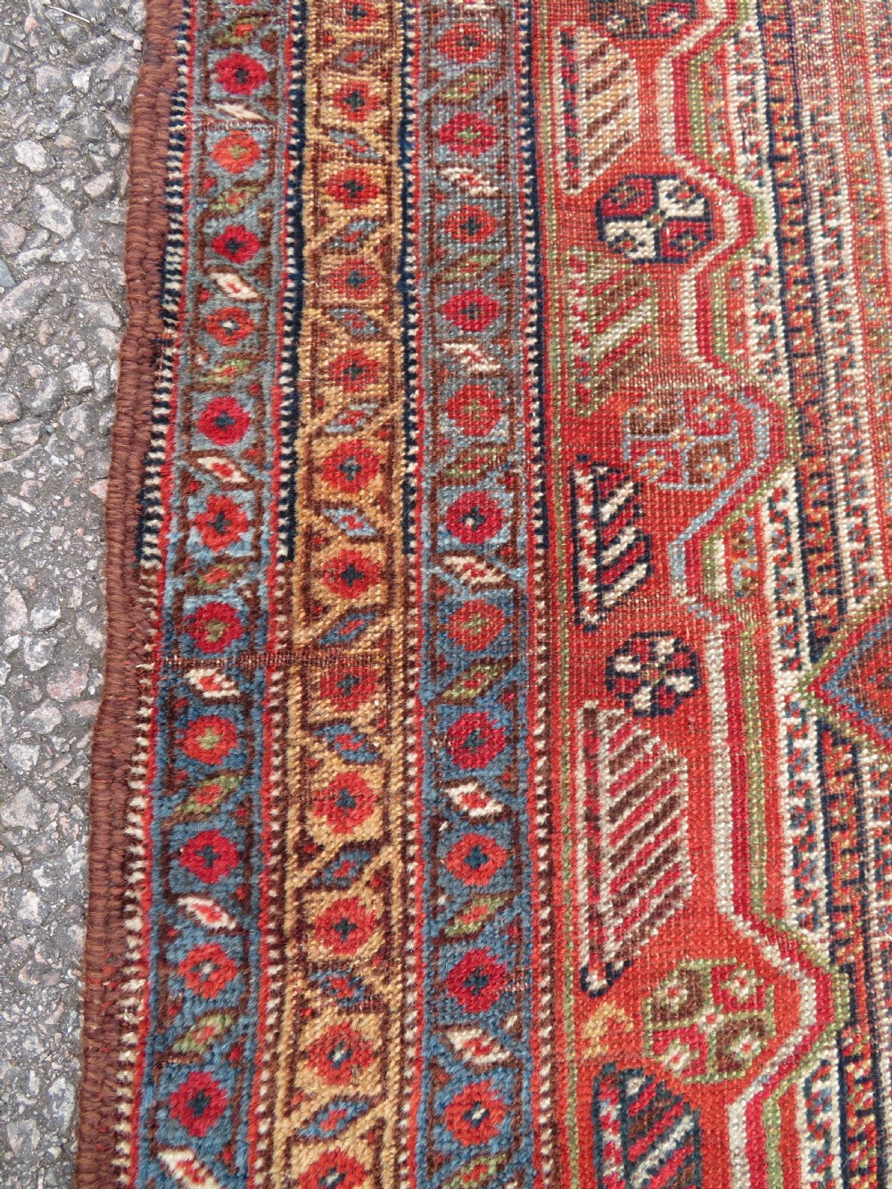 An antique hand-knotted South Persian Khamseh rug featuring a central diamond medallion surrounded by a striped field and geometric borders in shades of terracotta red, navy blue, and cream. View XVI