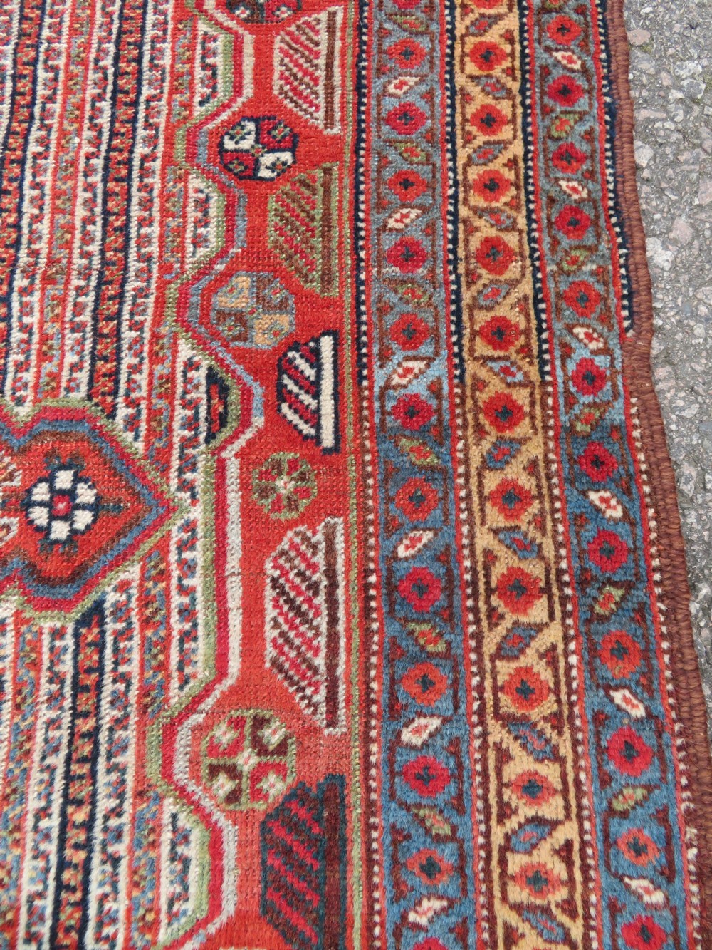 An antique hand-knotted South Persian Khamseh rug featuring a central diamond medallion surrounded by a striped field and geometric borders in shades of terracotta red, navy blue, and cream. View XX