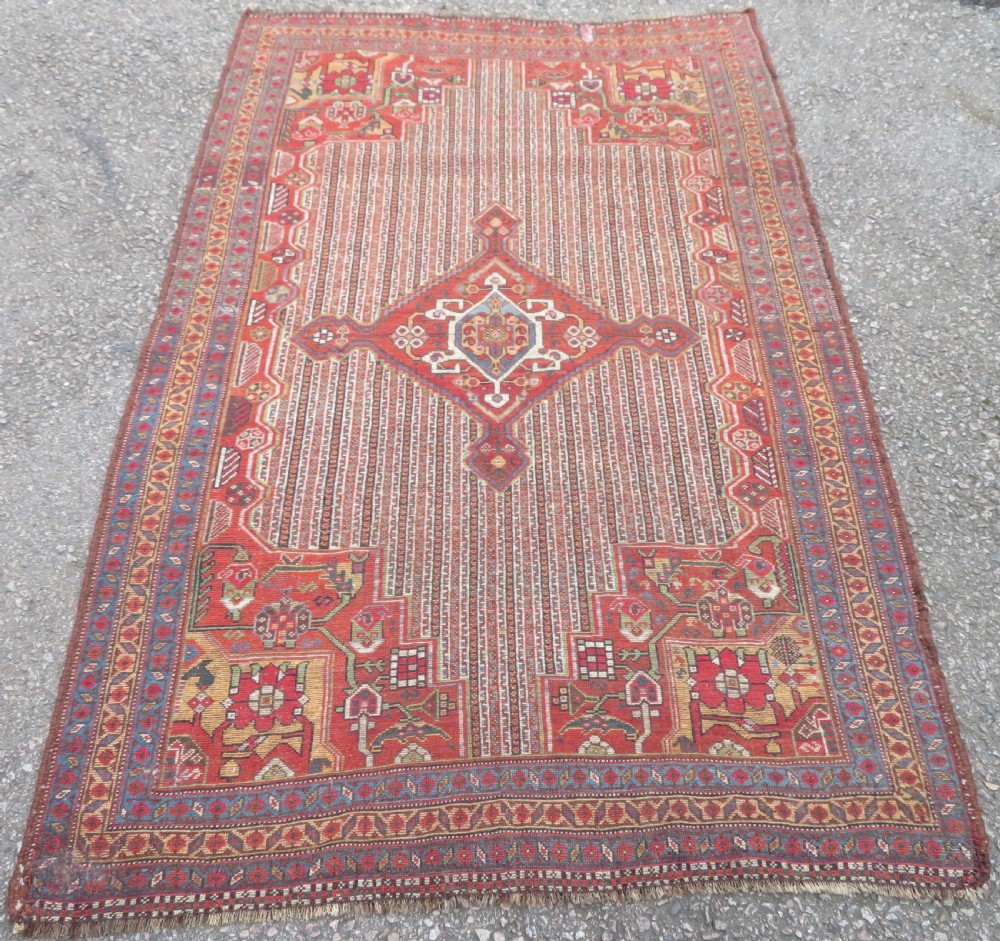 An antique hand-knotted South Persian Khamseh rug featuring a central diamond medallion surrounded by a striped field and geometric borders in shades of terracotta red, navy blue, and cream. View XXIV