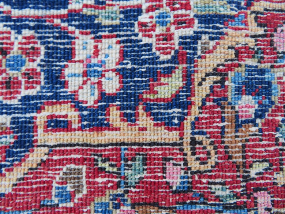 An antique hand-knotted Persian Kashan wool rug featuring a central ivory and red medallion surrounded by dense floral motifs on a dark blue field. View XXII