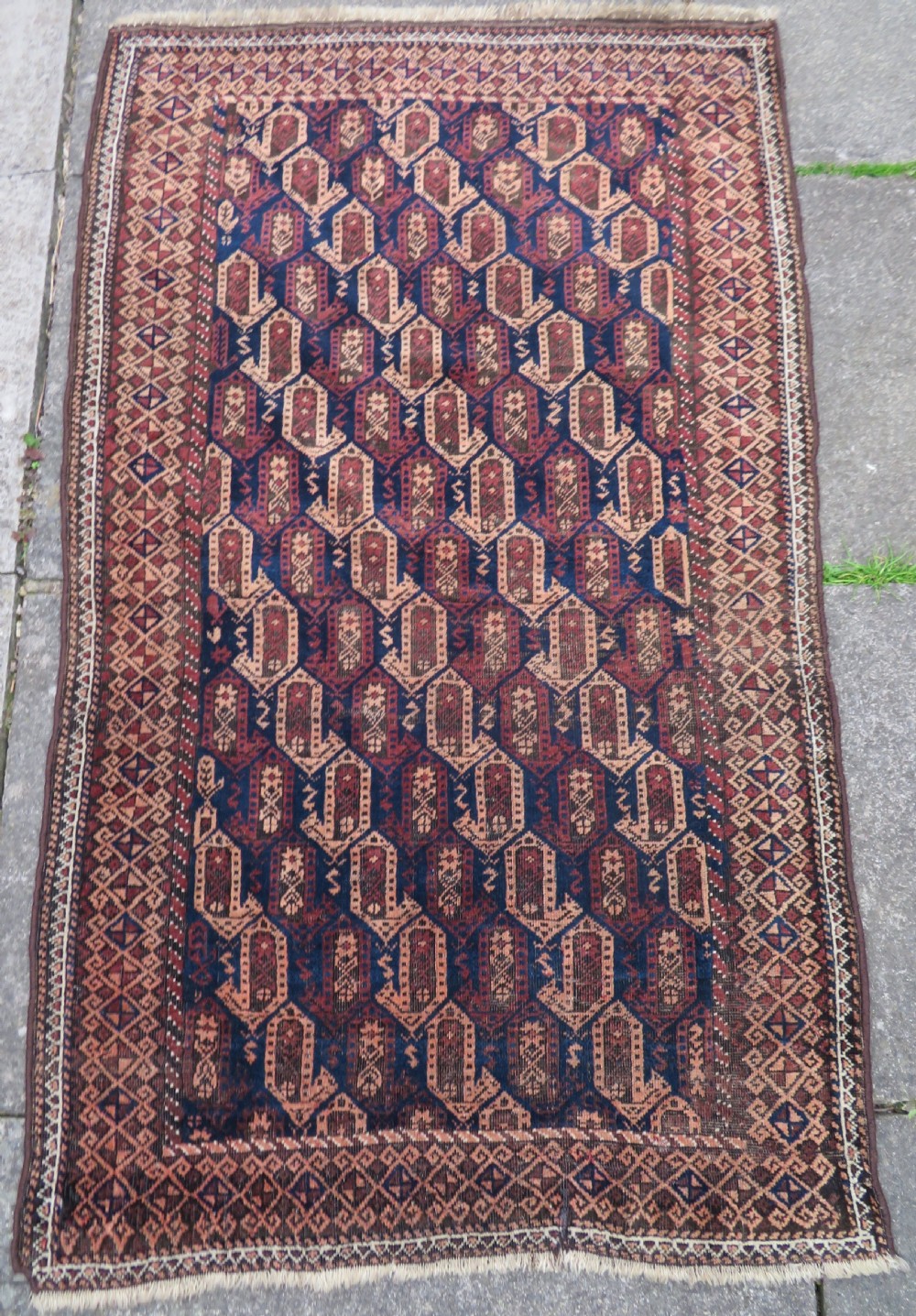 A hand-knotted antique Baluch rug featuring repeating geometric octagonal motifs in shades of dark blue, terracotta, and brown framed by patterned geometric borders. View II