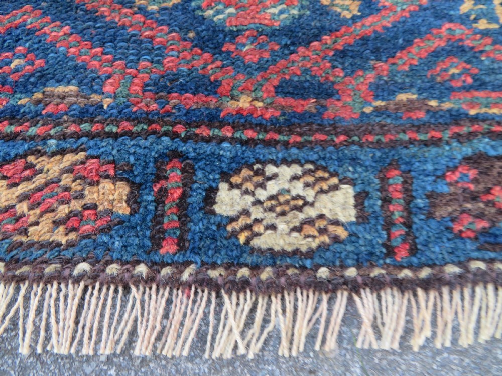 An antique Kurdish wool runner rug featuring geometric and stylized human figures in navy blue, madder red, and ochre with fringed ends. View XVI