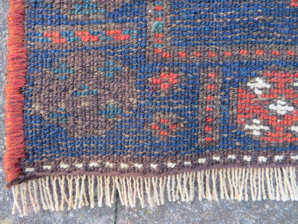 An antique Kurdish wool runner rug featuring geometric and stylized human figures in navy blue, madder red, and ochre with fringed ends. View XVIII