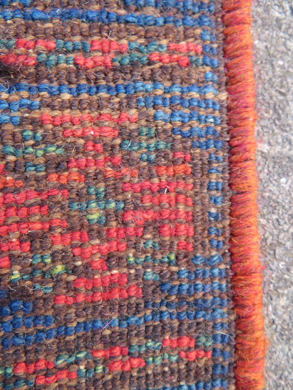 An antique Kurdish wool runner rug featuring geometric and stylized human figures in navy blue, madder red, and ochre with fringed ends. View XX