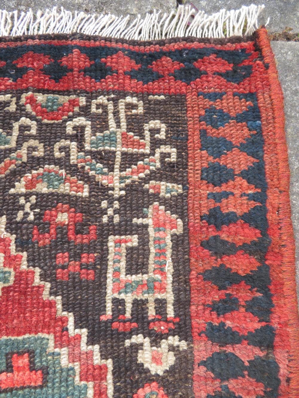 An antique hand-knotted Kurdish runner rug featuring five large geometric medallions in blue, red, and cream on a dark brown field. View VI