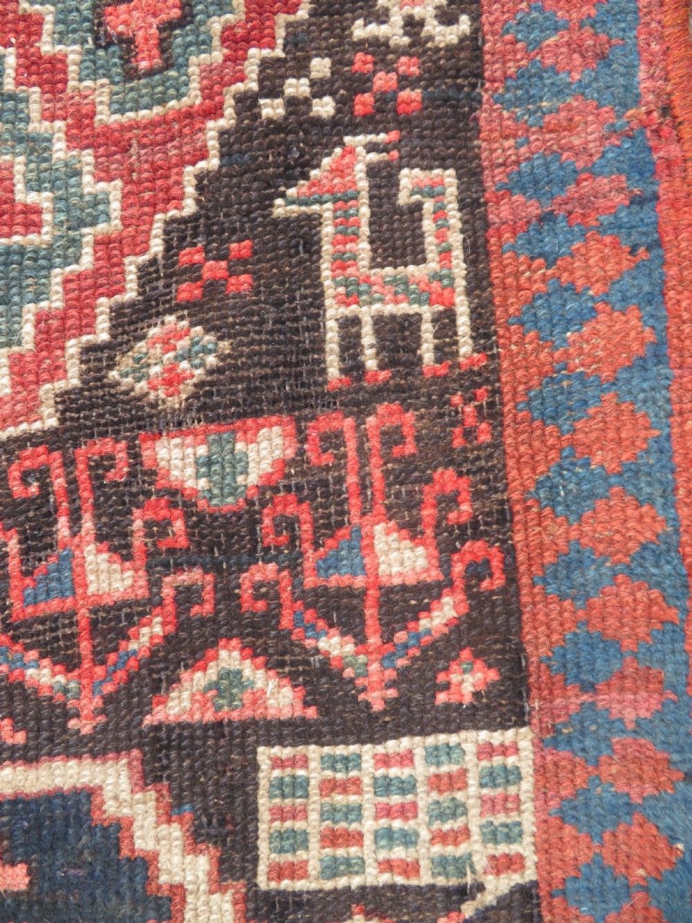 An antique hand-knotted Kurdish runner rug featuring five large geometric medallions in blue, red, and cream on a dark brown field. View VIII