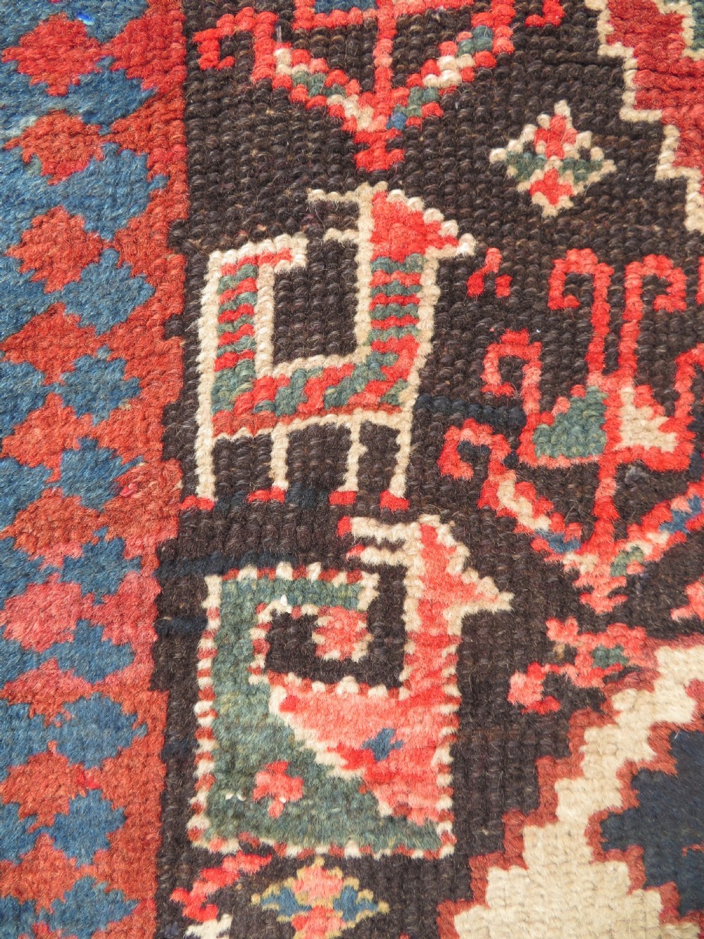 An antique hand-knotted Kurdish runner rug featuring five large geometric medallions in blue, red, and cream on a dark brown field. View IX