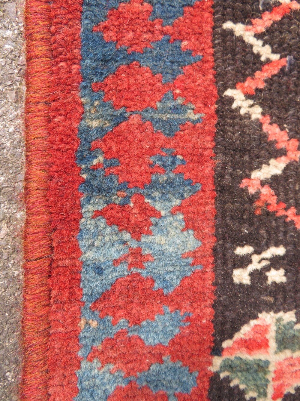 An antique hand-knotted Kurdish runner rug featuring five large geometric medallions in blue, red, and cream on a dark brown field. View X