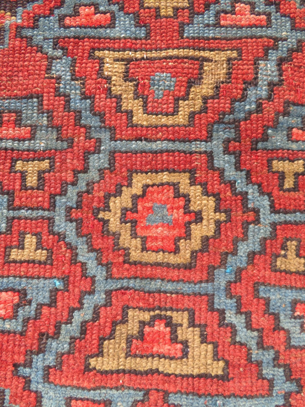 An antique hand-knotted Kurdish runner rug featuring five large geometric medallions in blue, red, and cream on a dark brown field. View XII