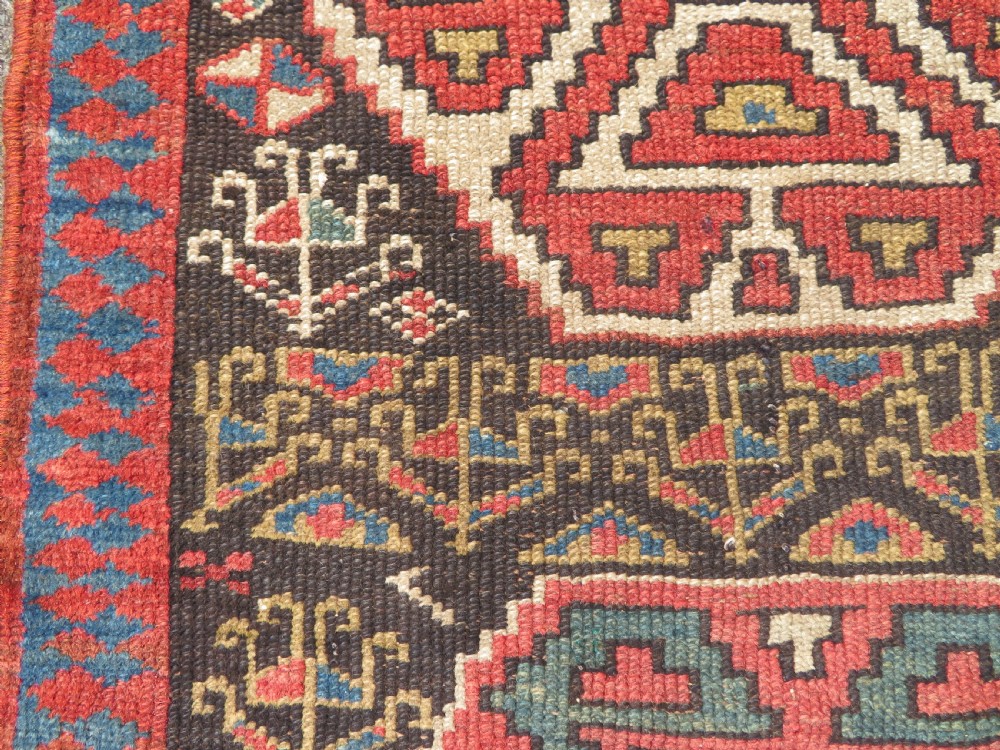 An antique hand-knotted Kurdish runner rug featuring five large geometric medallions in blue, red, and cream on a dark brown field. View XIII