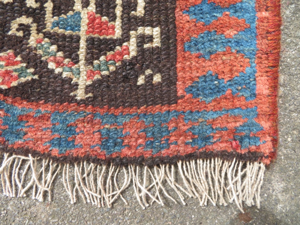 An antique hand-knotted Kurdish runner rug featuring five large geometric medallions in blue, red, and cream on a dark brown field. View XIV