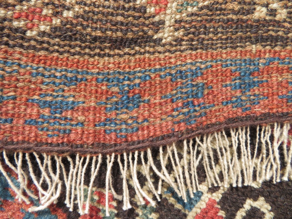An antique hand-knotted Kurdish runner rug featuring five large geometric medallions in blue, red, and cream on a dark brown field. View XVI