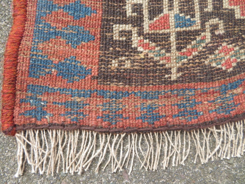 An antique hand-knotted Kurdish runner rug featuring five large geometric medallions in blue, red, and cream on a dark brown field. View XVIII