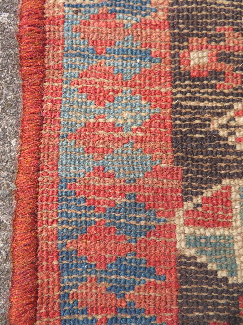 An antique hand-knotted Kurdish runner rug featuring five large geometric medallions in blue, red, and cream on a dark brown field. View XIX