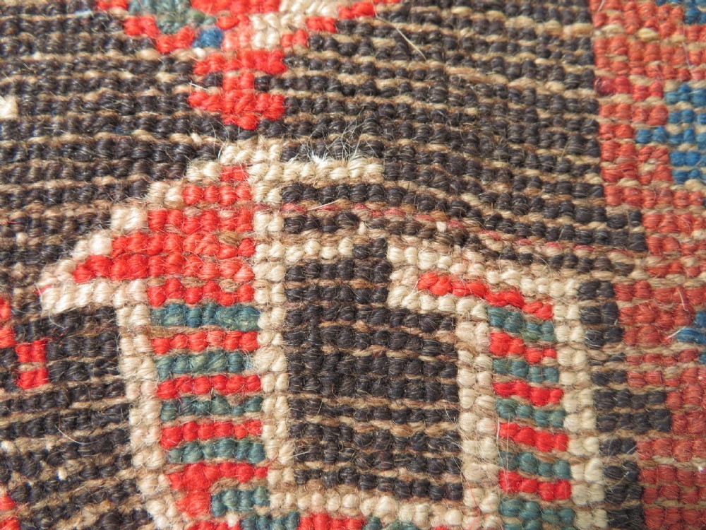 An antique hand-knotted Kurdish runner rug featuring five large geometric medallions in blue, red, and cream on a dark brown field. View XX